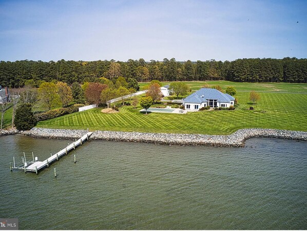 A large house with a swimming pool, surrounded by a well-maintained lawn and a dock extending into a lake. - Sunset Shores | an ESVR property (Royal Oak)