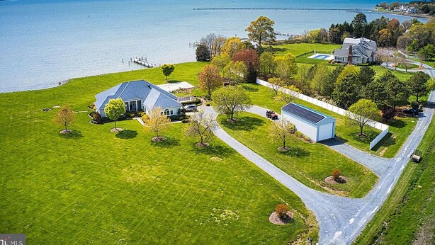An aerial view of a residential area with a large house, a smaller house, and a dock extending into a lake. - Sunset Shores | an ESVR property (Royal Oak)