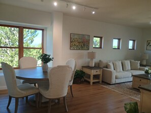 Un soggiorno con tavolo da pranzo, sedie, divano, lampada e un quadro appeso al muro.