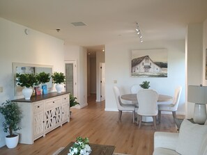 Ein Essbereich mit Tisch und Stühlen, eine Kommode mit Dekoration und ein Bild an der Wand.