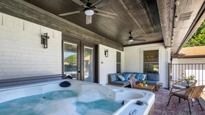 A spa area with a hot tub, ceiling fans, and a seating area with a sofa and chairs. - Backyard Oasis: Pool, Hot Tub, Giant Chess & Golf (Fort Worth)