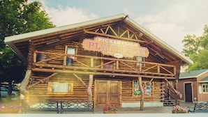 A rustic log cabin with a sign reading "Pickleville Playhouse 1977".