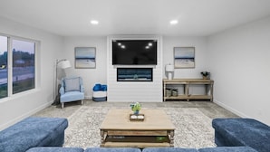 A living room with a TV, sofa, armchair, and a coffee table.