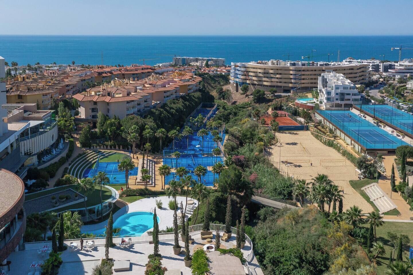 Ein Resort mit mehreren Schwimmbecken, einem Strandbereich und Meerblick.