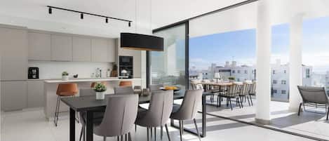 A modern apartment with a dining area, kitchen, and a balcony with a city view.