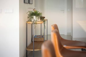 A modern interior with a plant on a metal stand, a wicker basket, and a wooden chair. - Luxury 3-Bedroom Apartment in Higuerón (La Capellania)