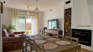 A dining area with a wooden table and chairs, a television, and a fireplace.