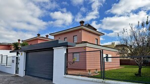 A two-story house with a closed garage door, a fenced yard, and a clear sky.
