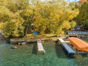 A clear lake with a dock and a covered seating area.