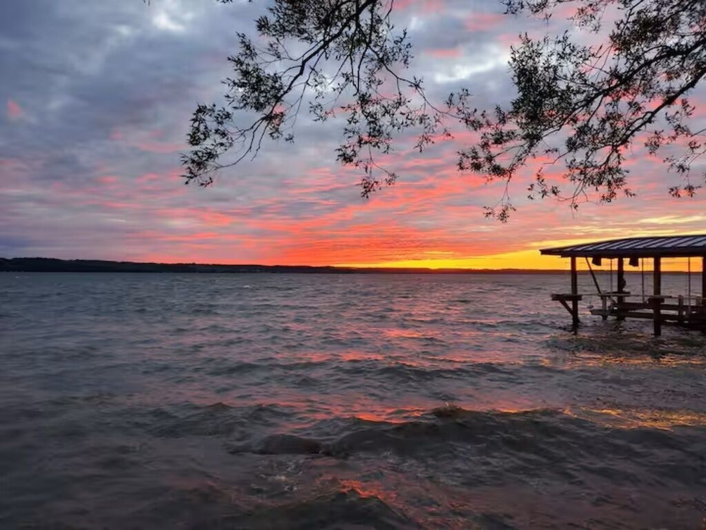 A sunset over a body of water with a wooden structure on the right.
