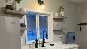 A modern kitchen with a double sink, a refrigerator, and a window with a view of a snowy landscape. - Cayuga Lake Cottage near Aurora - Wineries, Brewery, Trails and Lakefront. (Aurora)
