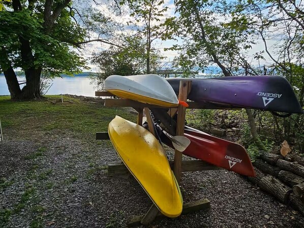 A row of canoes on a stand near a lake.