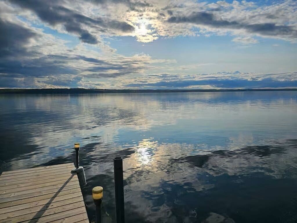 A calm lake with a wooden dock extending into the water.