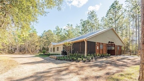 A cabin with a covered porch, a garage, and a dirt driveway.