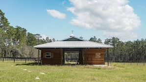 Une petite cabane en bois avec un toit en métal, une entrée abritée et une zone délimitée par une clôture.