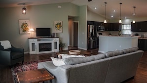 Un salon moderne avec un canapé, un téléviseur et une cheminée.