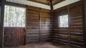 Un intérieur stable avec des murs en bois, un plancher à lattes et un toit en métal.