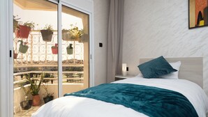 A hotel room with a bed, a nightstand, a window with a view of a balcony with potted plants. - Mina Home minutes from City Center and beach (Agadir)