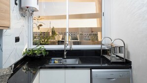 A modern kitchen with a Bosch dishwasher, a sink with a faucet, and a window overlooking a balcony with potted plants. - Mina Home minutes from City Center and beach (Agadir)