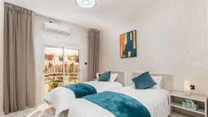 A hotel room with two beds, a balcony with a view, an air conditioning unit, and a modern decor. - Mina Home minutes from City Center and beach (Agadir)