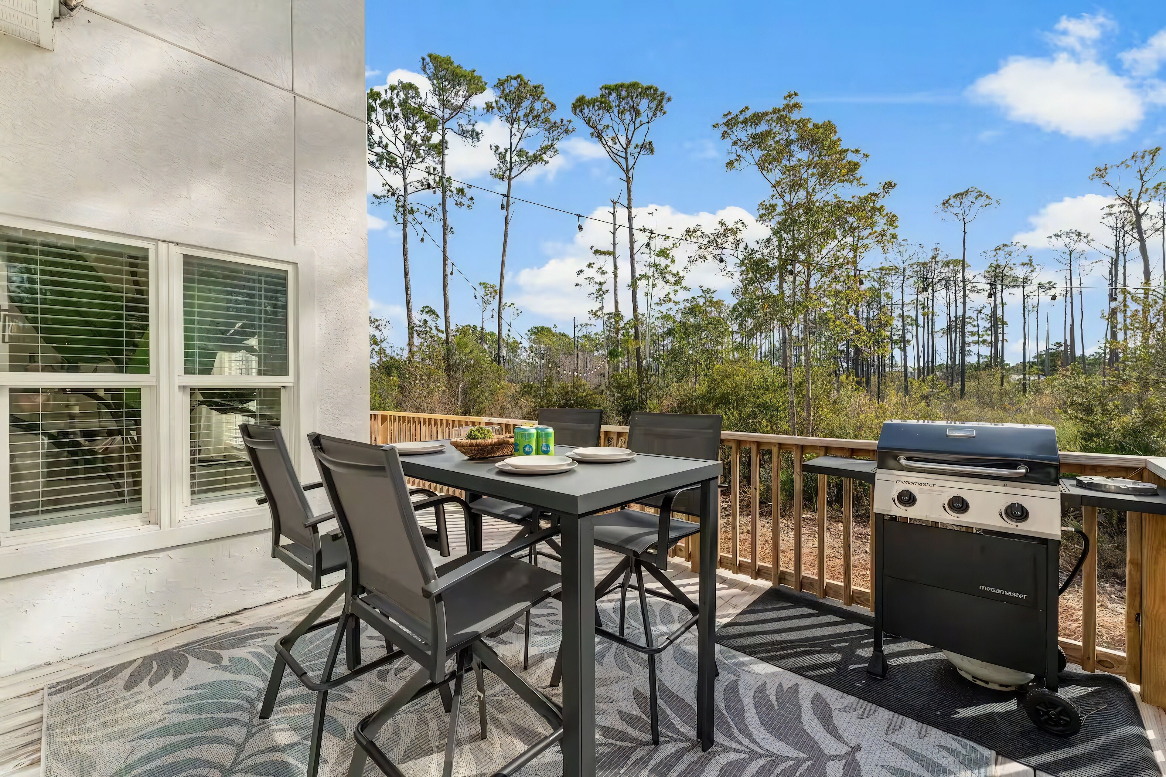 Patio con barbecue, tavolo, sedie e vista sugli alberi.