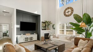Een moderne woonkamer met een grote flatscreen-tv, een open haard en een groot raam met uitzicht op de stad.