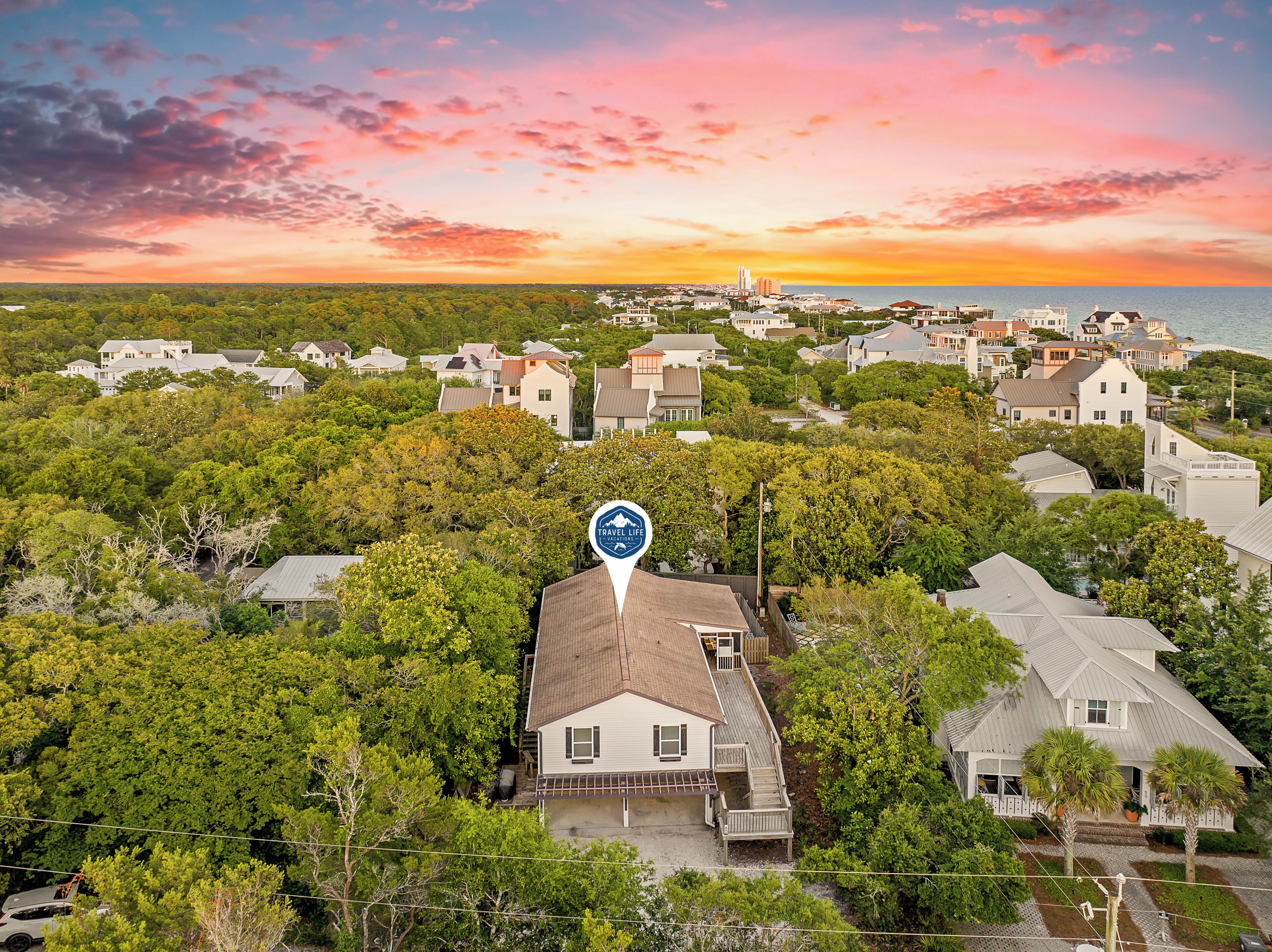 A residential area with houses surrounded by trees, a clear sky, and a sunset.