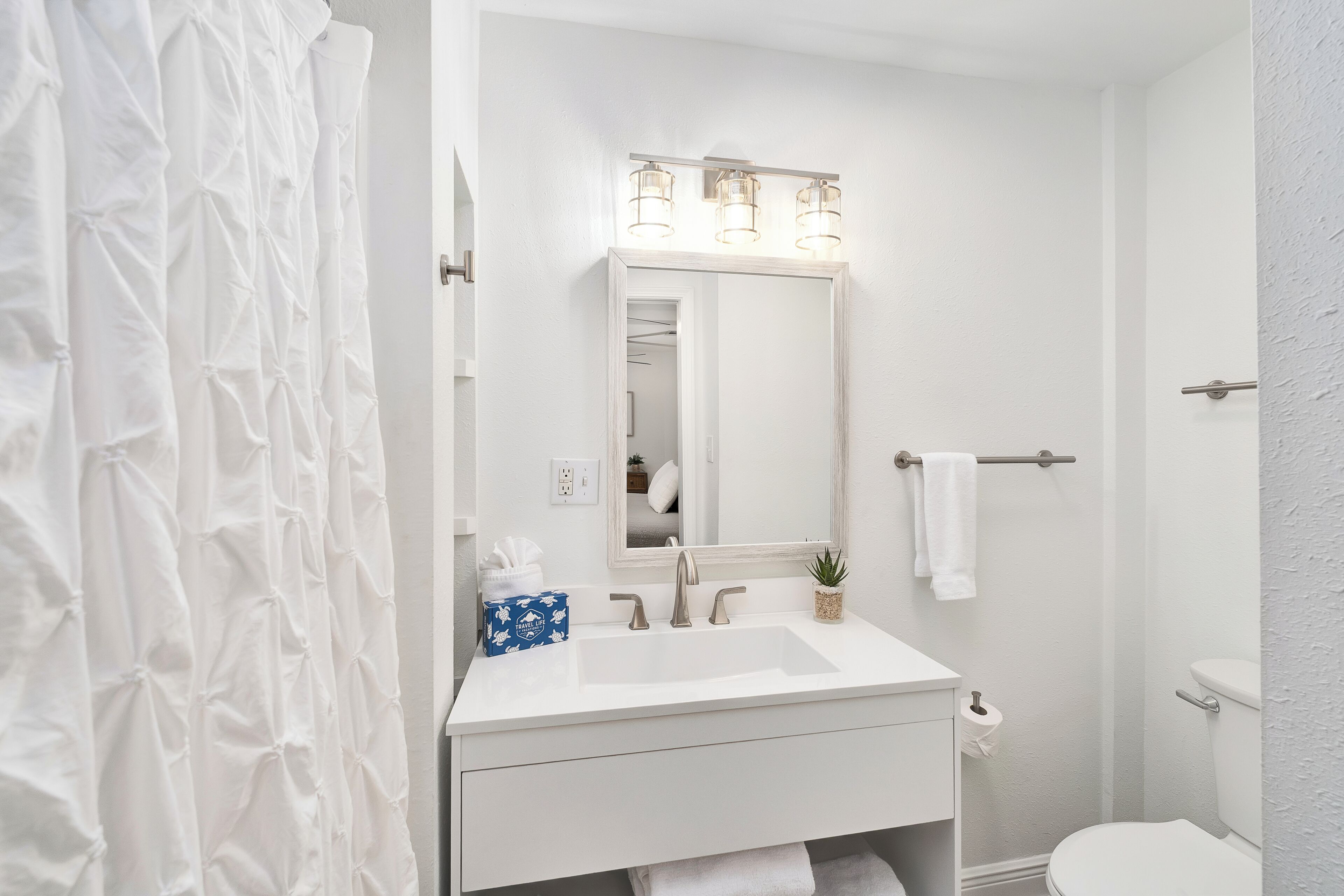A bathroom with a white sink, mirror, and light fixture.