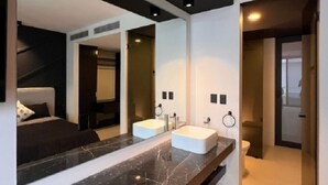 Un baño moderno con un espejo grande, dos lavamanos y un inodoro.