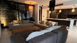 Una sala de estar moderna con un sofá gris, una mesa de centro de madera y una pared decorativa de piedra.