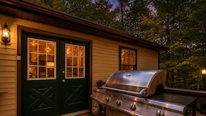 Eine Holzterrasse mit Grill und einer grünen Tür mit Fenstern.