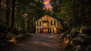 Ein zweistöckiges Haus mit Veranda, umgeben von einem Wald.