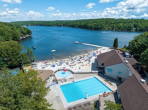 Un resort con piscina, zona de playa y barcos en un lago.