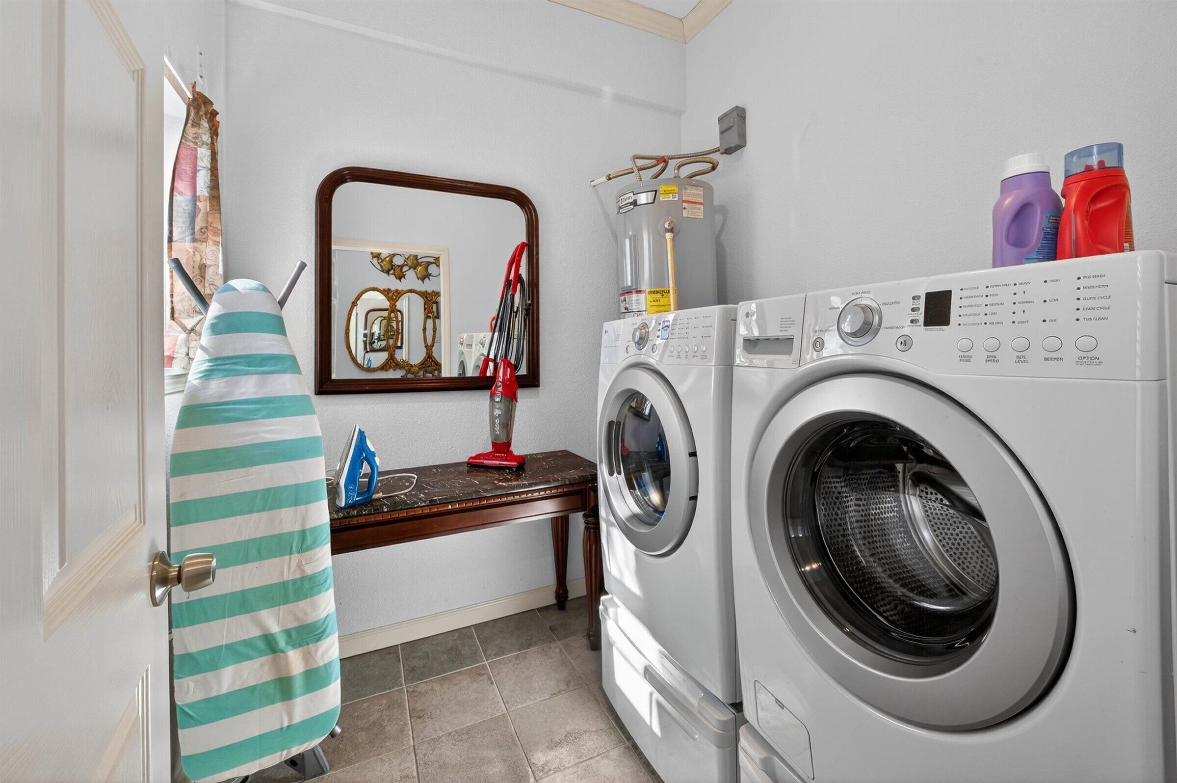 A laundry area with a washing machine, ironing board, and ironing board cover.