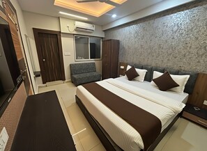 A modern hotel room with a large bed, a sofa, a desk, and a wardrobe. - The Samsara Hotel (Indore)
