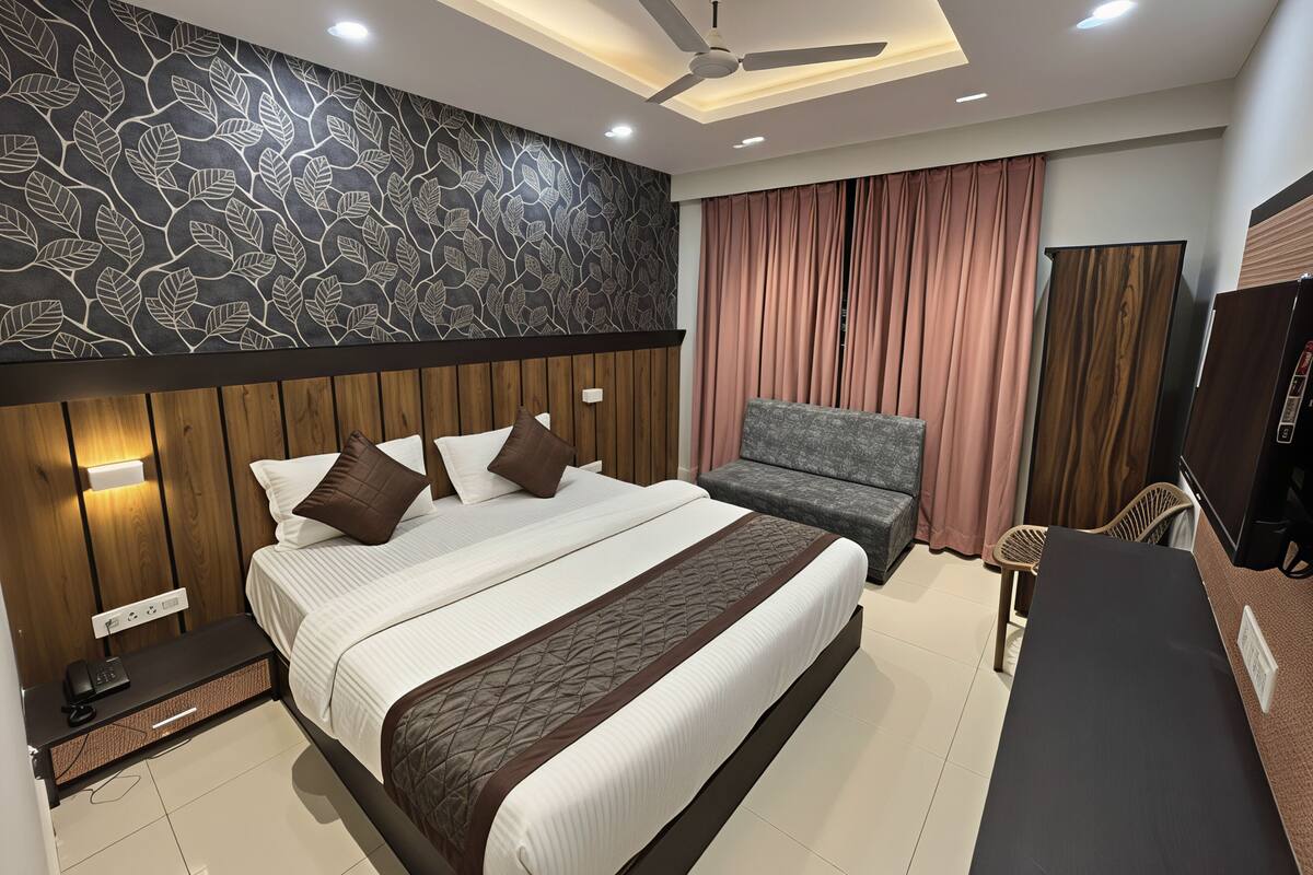 A modern hotel room with a large bed, a sofa, a desk, and a TV.