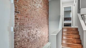 A staircase with wooden steps leading to a bedroom with a bed and a nightstand.