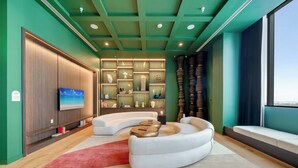 Ein modernes Wohnzimmer mit einem gebogenen weißen Sofa, einem roten Teppich und einem Fernseher an der Wand.