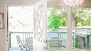 A room with a glass door leading to an outdoor deck with chairs and a table. - Waterfront Sonoma Russian Rvr Lux Vineyard Ranch on Creek, Pool+HotTub+Bocce+Pet (Sebastopol)