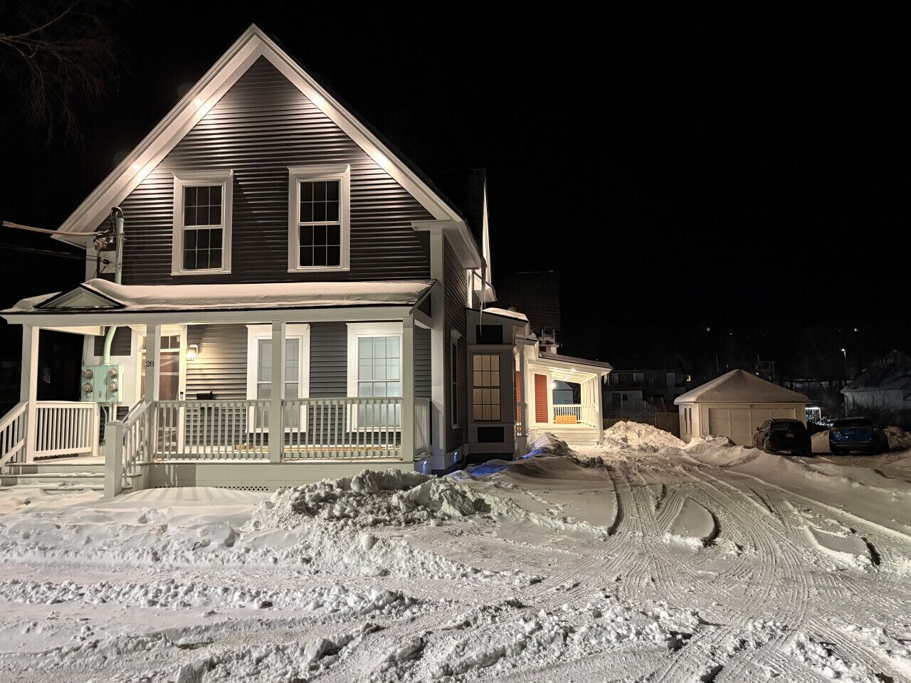 A two-story house with a porch and a garage, surrounded by snow.