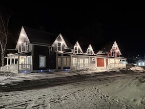 Een rij huizen met een overdekte veranda, een garage en een oprit, besneeuwd.