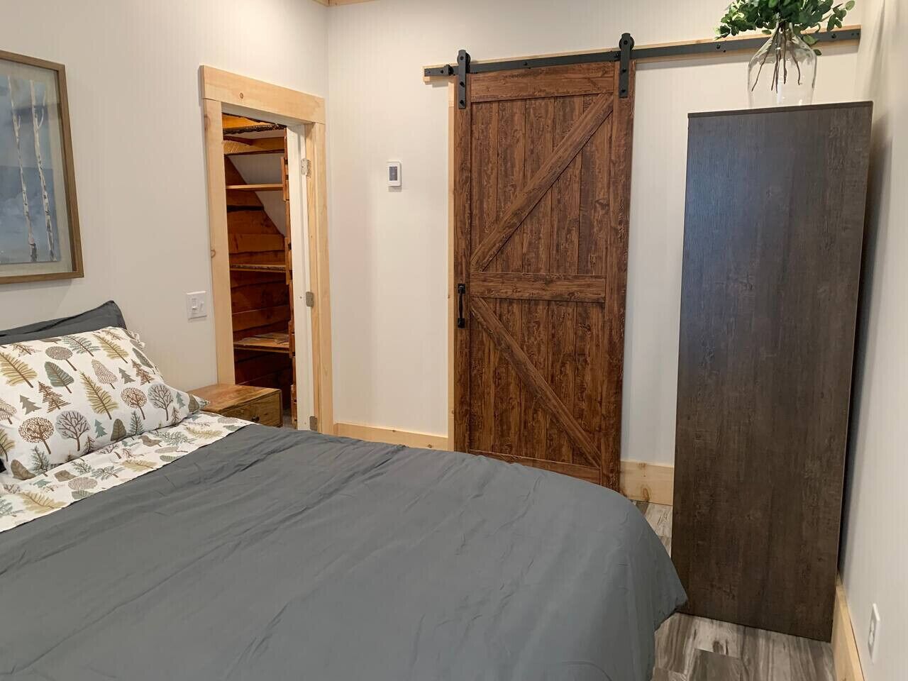 A bedroom with a bed, a wooden sliding door, a closet, and a large dark panel.