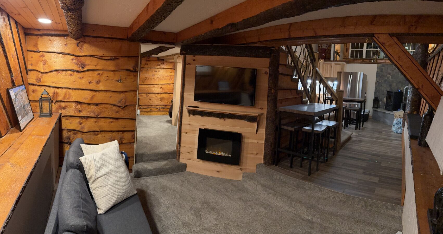 A cozy log cabin interior with a fireplace, a sofa, and a dining area.
