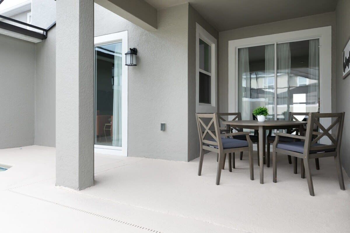 A patio area with a table and chairs, a potted plant, and a sliding glass door leading to an interior space.