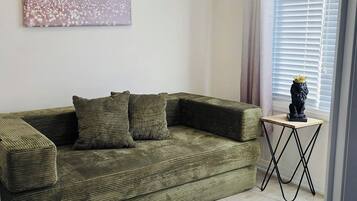 A living room with a sectional sofa, a small table, and a decorative statue.