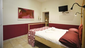 A bedroom with a bed, a painting, a bookshelf, a television, and a telephone. - RIPA HOME LOFT IN TRASTEVERE (Roma)