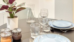 Una mesa redonda para comer dispuesta con platos azules, vasos transparentes y una planta en maceta.