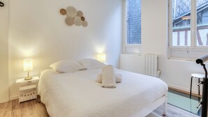 Un dormitorio moderno con una cama grande, lámparas de noche, una ventana con vistas y un elemento decorativo en la pared.