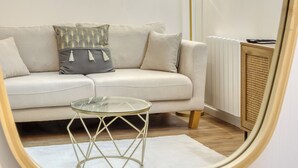 Una sala moderna con sofá, una mesa de centro de cristal, una lámpara de pie y un radiador.