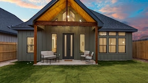 A modern house with a covered porch, a well-maintained lawn, and a wooden fence. - New! 4 BDRM Home near stockyards & DT Fort Worth (Fort Worth)